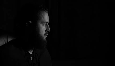 Dramatic black and white portrait of a bearded man in profile with intense ga Stock Photos