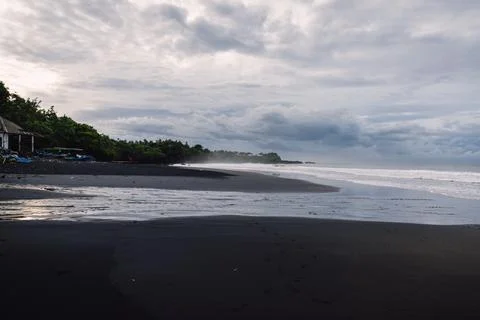 Dramatic black sand beach under stormy clouds on a tropical coastline Foto stock
