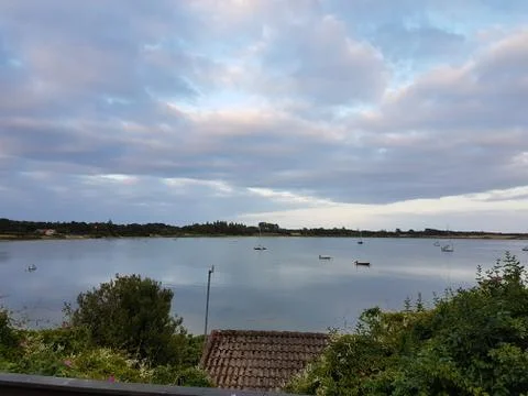 Dramatic blue and cloudy sky reflecting in  the ocean with small boats Stock-Fotos
