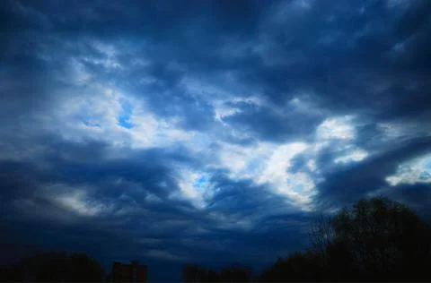 Dramatic blue clouds with black silhouettes background Foto stock