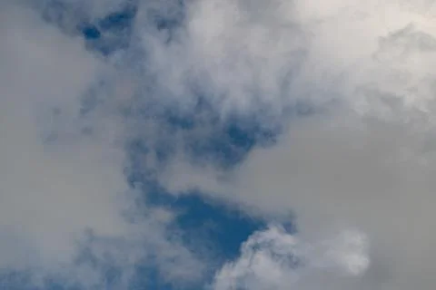 Dramatic blue gap breaking through clouds, sunlit core contrasted with shadow Foto stock