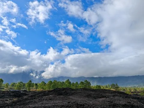 Dramatic blue sky and thick white clouds over Mount Batur black volcanic lava Stockfoto's