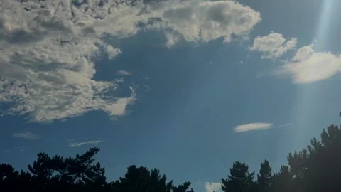 Dramatic blue sky with bright sunlight and scattered clouds above forest Stock Footage 337104798