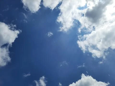 Dramatic Blue Sky with Bright White Clouds and Sunlight. Stock Photos