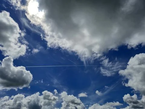 Dramatic blue sky with clouds and contrail Stock Photos