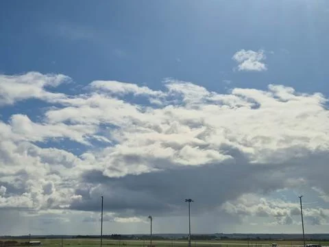 Dramatic blue sky with large clouds over rural fields Stock Photos