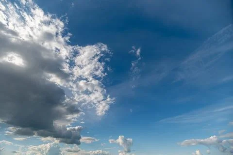 Dramatic blue sky with scattered clouds and sunlight Stock Photos