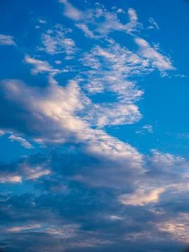 Dramatic Blue Sky with Scattered White and Golden Sunlit Clouds, Vertical N.. 写真素材