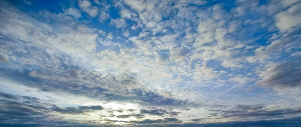 Dramatic blue sky with textured clouds at sunset over the horizon Stock Photos