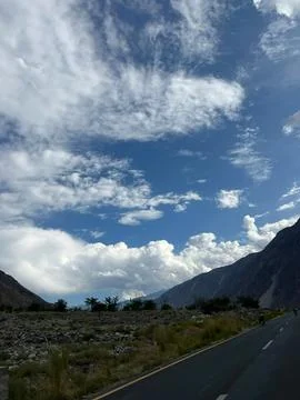 Dramatic Blue Sky with White Clouds over  Mountains and Highway in Nomal Gilgit Stock Photos