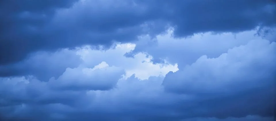 Dramatic blue storm clouds clearing to reveal patch of bright sky, weather .. Stock Photos