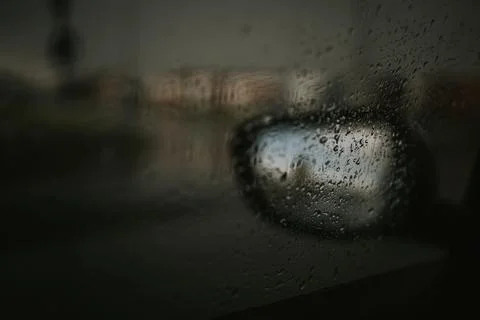 A dramatic blurred shot of the side mirror of a car seen through a window cov Stock Photos