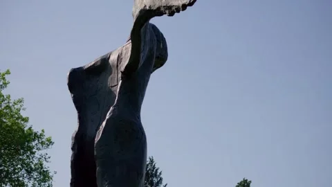 Dramatic bronze winged sculpture reaching towards the clear blue sky in Stock Footage 338440821