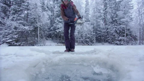DRAMATIC CHAINSAW WOMAN ACTION - cutting ice bathing hole Stock Footage 167075236