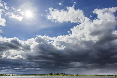 Dramatic changeable weather on the lake with cloudy sky, sun, cloud, light Stock Photos