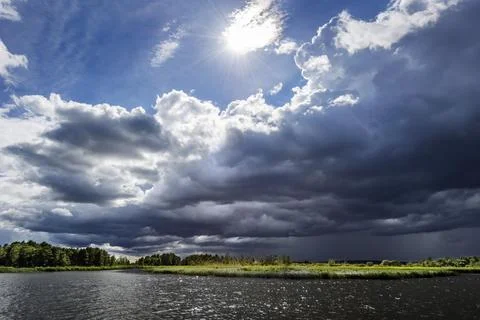 Dramatic changeable weather on the lake with cloudy sky, sun, cloud, light Stock Photos