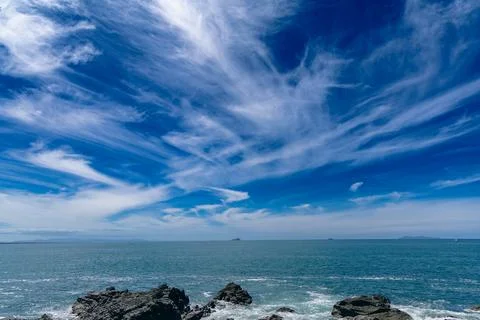 Dramatic Cirrus Clouds Above Rocky Coastal Seascape Foto stock