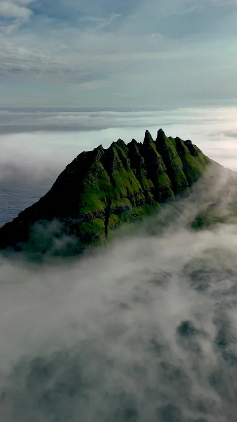 Dramatic cliffs of Drangarnir enveloped in mist over the serene waters of the Stock Footage 315290992