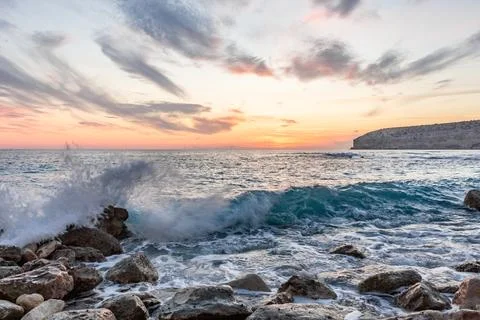 Dramatic cliffs meet the gentle waves at twilight, a lonely rock standing sen Foto stock