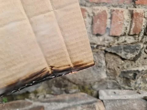 Dramatic Close Up of Cardboard Sheet on Fire With Ashes Stock Photos