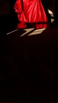 Dramatic close-up of a flowing red satin dress hem illuminated by sunlight .. Foto stock