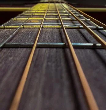 Dramatic Close-Up of Guitar Strings and Frets with Warm Light Foto stock