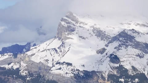 A dramatic close-up view of a rugged snow-covered mountain peak in the Alps Stock Footage 346702302