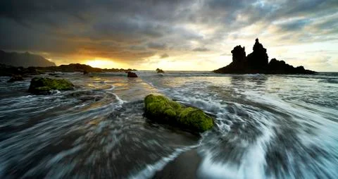 Dramatic cloud atmosphere with rock formation at sunset on the beach of Playa Stock Photos