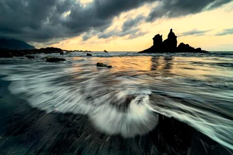 Dramatic cloud atmosphere with rock formation at sunset on the beach of Playa Stock Photos