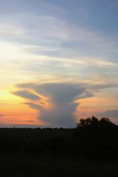 Dramatic cloud formation at sunset with dark silhouette landscape Stock Photos