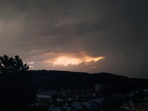 Dramatic cloud formations over a hillside town in the late afternoon sunlig.. Stock Photos
