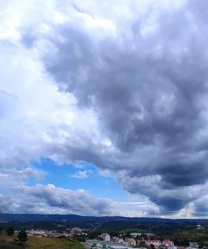 Dramatic cloud formations over a hillside town in the late afternoon sunlig.. 스톡 사진