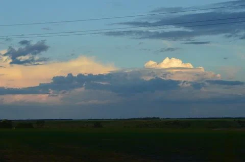 Dramatic cloud formations over a vast landscape at sunset with a hint of pastel Stock Photos