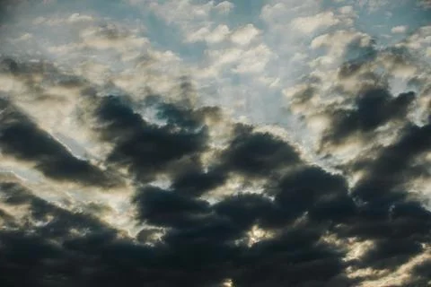 Dramatic cloud formations with varying shades of gray and blue illuminated .. Stock Photos