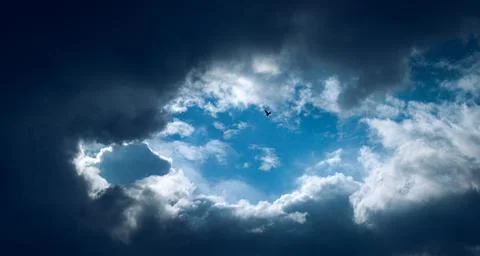 Dramatic cloud gathering, blue sky in the middle, a bird fly high up in the s Stock Photos