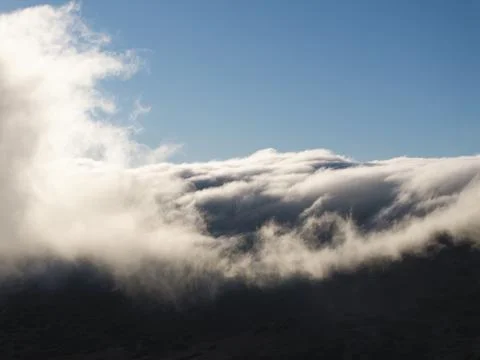 Dramatic cloud inversion blankets mountain peaks under a clear blue sky Fotos de archivo