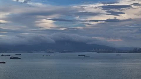 Dramatic cloud layer rolling over mountains xiamen strait with cargo ships Foto stock