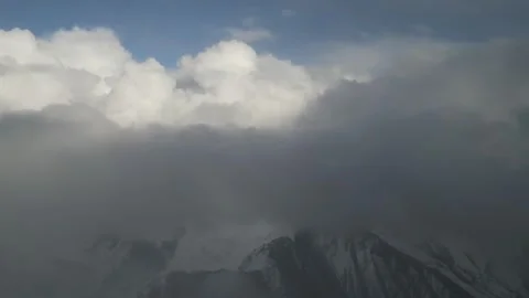 Dramatic cloud movement over snow-capped mountains with gradual reveal Stock Footage 323301813