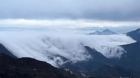 Dramatic cloud waterfall flowing across mountain peaks time lapse Stock Footage 333158605