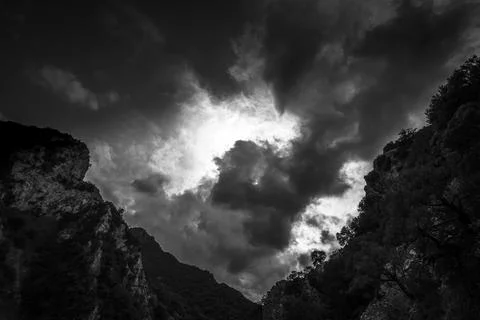 DRAMATIC CLOUDS ABOVE SLOPES. Black and white view on sunlight mountains in c Stock Photos