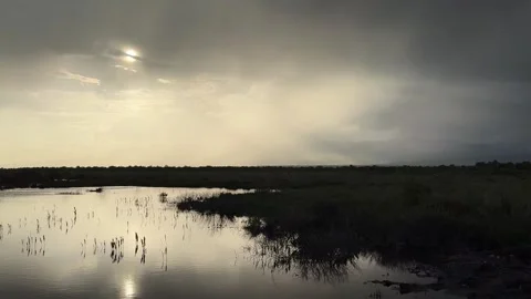 Dramatic Clouds and Sun Reflecting on a Serene Marshland in China at Sunset 스톡 동영상 336857627