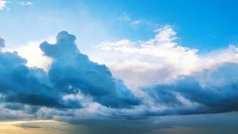 Dramatic clouds in a blue sky with a hint of sunlight peeking through Stock Photos