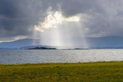 Dramatic clouds break above calm sea water, natural landscape Stock Photos