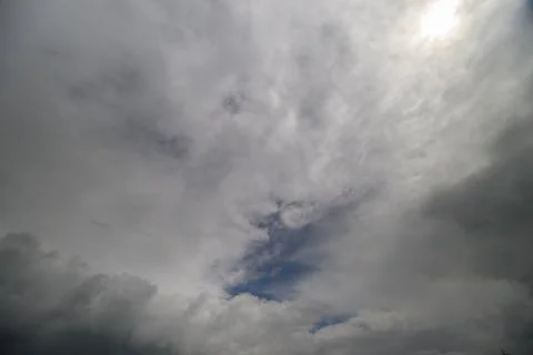 Dramatic clouds dance across the sky, revealing glimpses of blue as dayligh.. Stock Photos