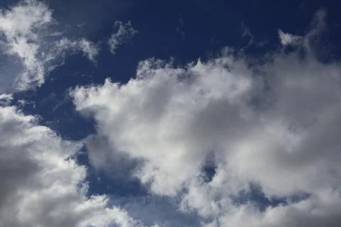 Dramatic clouds in a deep blue sky, perfect for backgrounds and nature themes Stock Photos