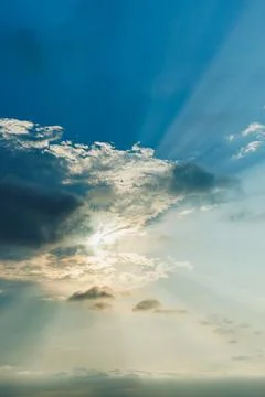 Dramatic clouds drift across the evening sky, with sunlight breaking through  Stock Photos