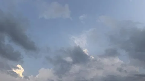 Dramatic clouds drift across a pale blue sky. Foto stock