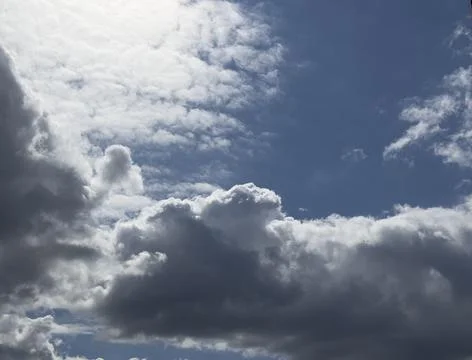 Dramatic clouds fill a blue sky. Bright and dark cloud layers create a strong 写真素材