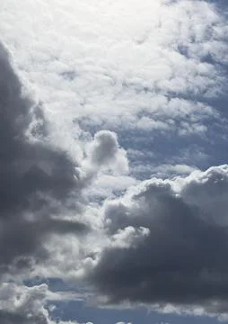 Dramatic clouds fill a blue sky. Bright and dark cloud layers create an Stock Photos