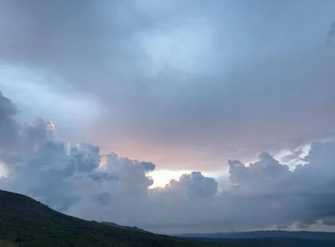 Dramatic clouds fill the sky over a quiet landscape at dusk Stock Photos